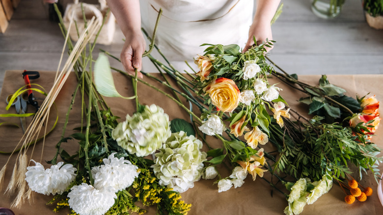 Hand holding flowers with scissors nearby