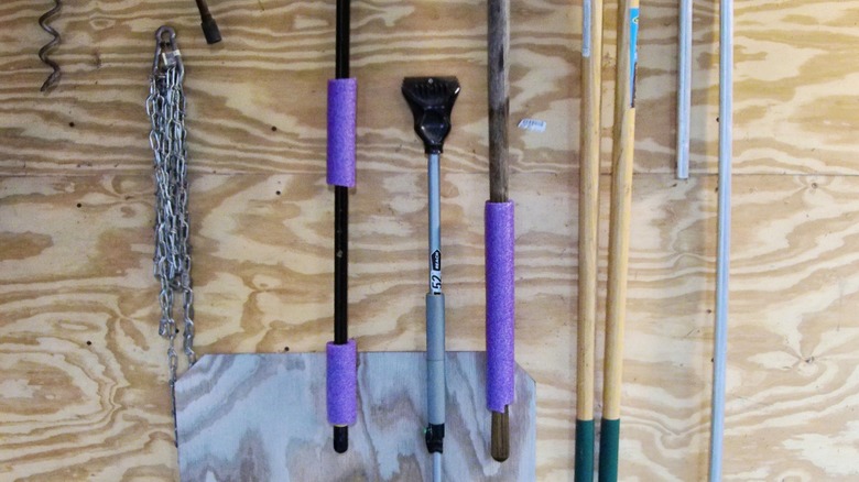purple pool noodles on handles of yard tools