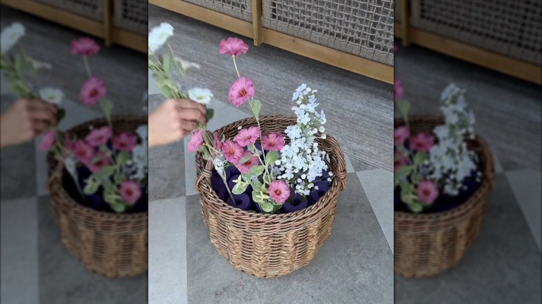 a woman placing flowers into pool noodle holes in a basket