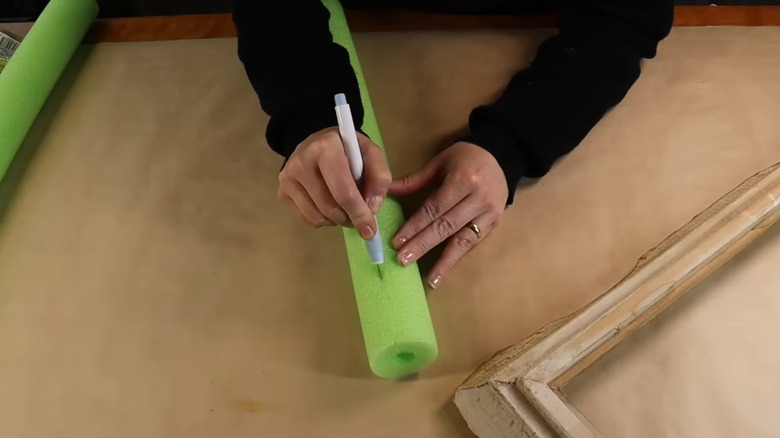 Someone cutting into a green pool noodle for a DIY