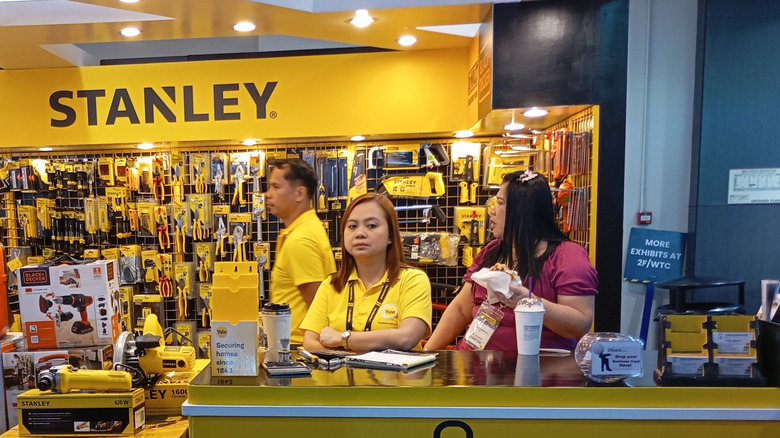 Salespeople standing behind a desk near a Stanley tool display