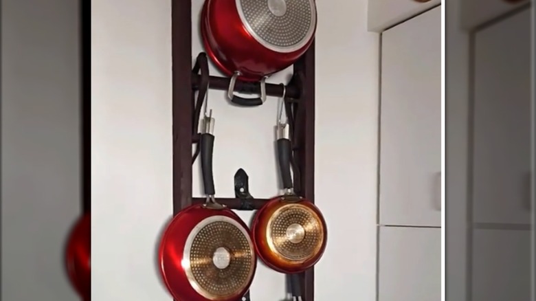 Red cookware hanging on an upcycled wooden ladder.