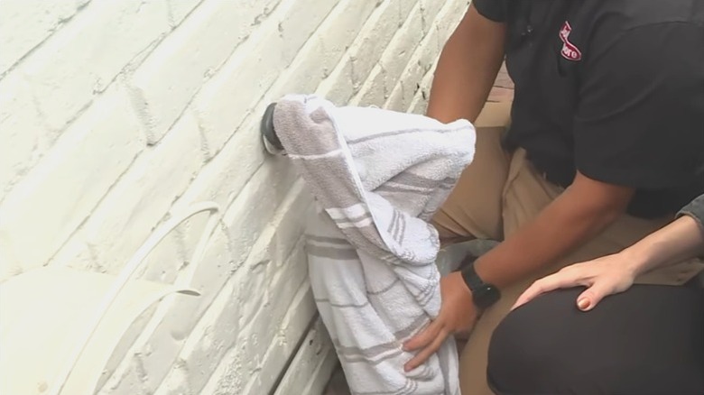 people covering exterior water pipe with blanket