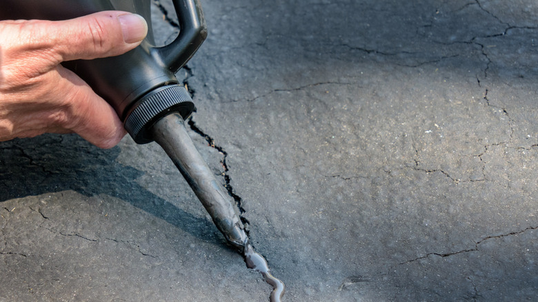 A hand applying sealer to concrete.
