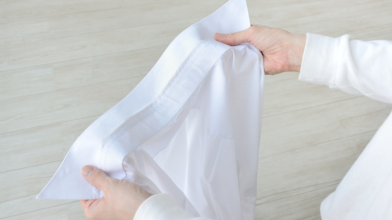 Person examining a white button-down shirt