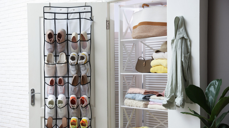 An over-the-door hall closet organizer is filled with shoes