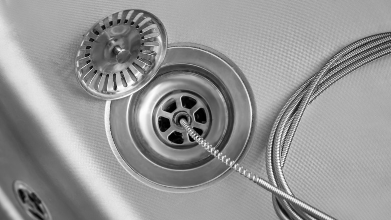 A drain snake going into a drain