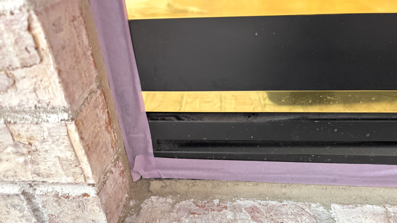 Purple tape lined up around the bottom of a fireplace