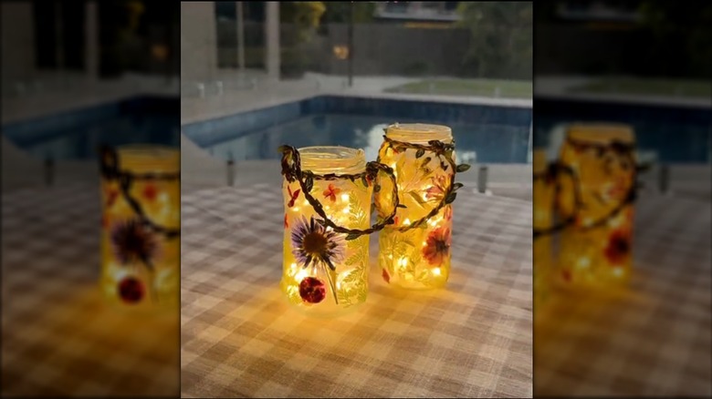 DIY lanterns made from glass jars and dried flowers on gingham tablecloth on porch