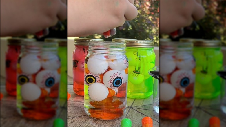 Person mixing highlighter ink and Halloween decor in glass jar for unique, one-of-a-kind decor outside
