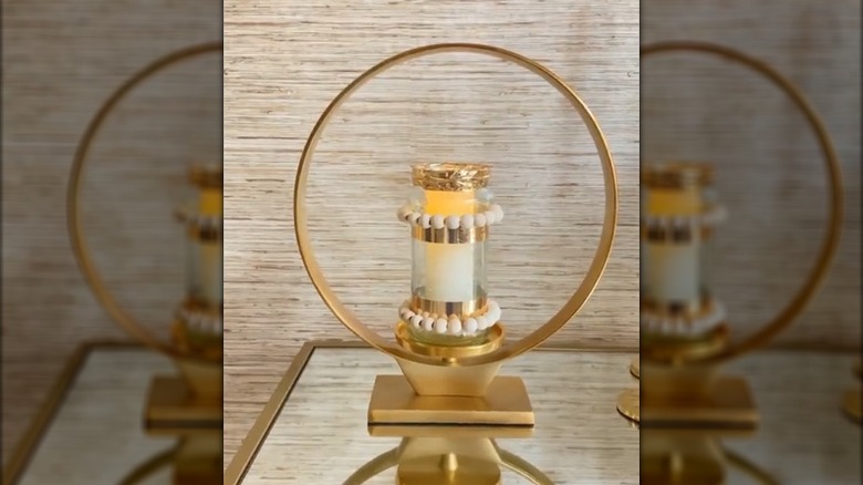 Elegant gold candle holder made from tape, beads, and an old glass jar on glamorous glass table