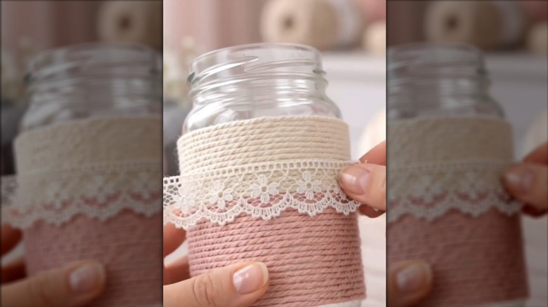 Woman wrapping glass jar with pastel-colored twine and lacey ribbon