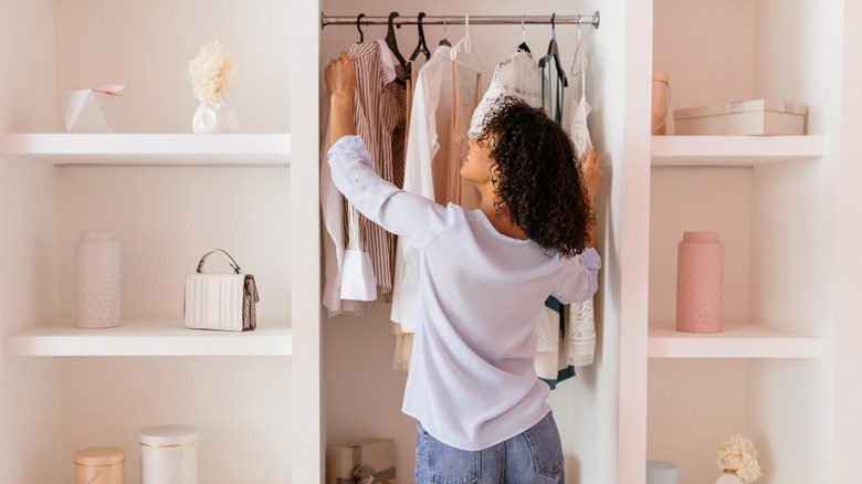 A woman opens a closet in an airy room