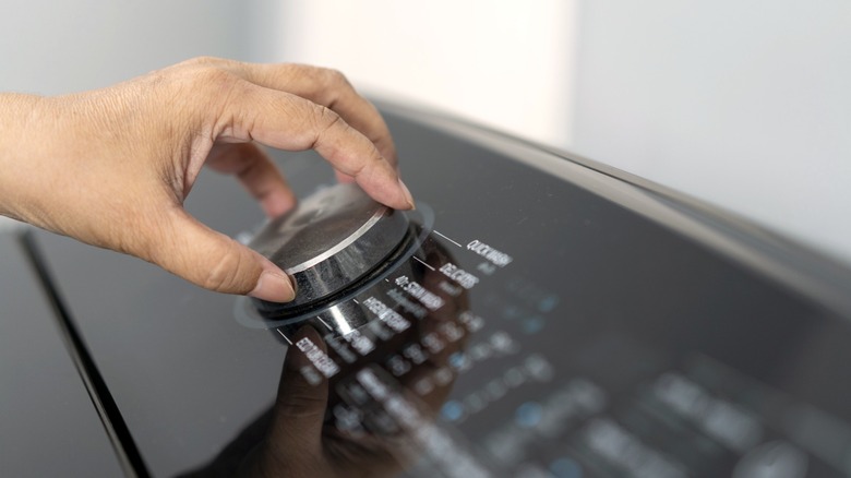 person adjusting wash settings on washing machine
