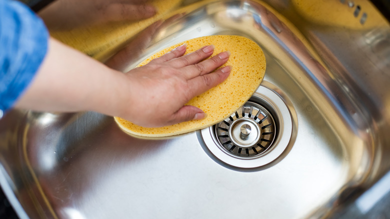 Someone cleaning the interior of a stainless sink