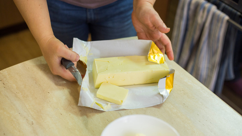 Person unwrapping a large slab of butter