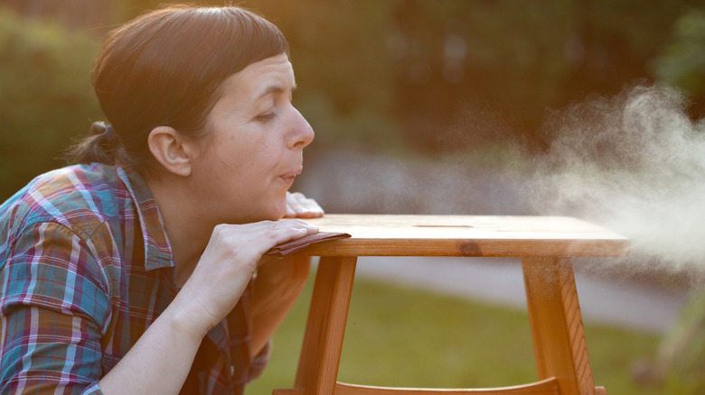 woman blowing off sanding dust