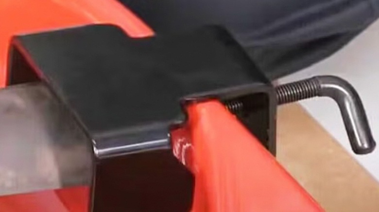 Blade removal tool clamped onto lawnmower housing and holding the blade steady