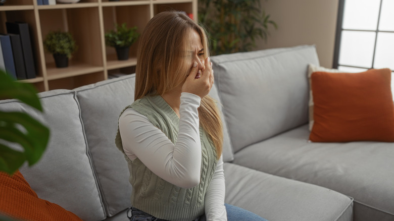 Woman on a couch noticing a bad smell