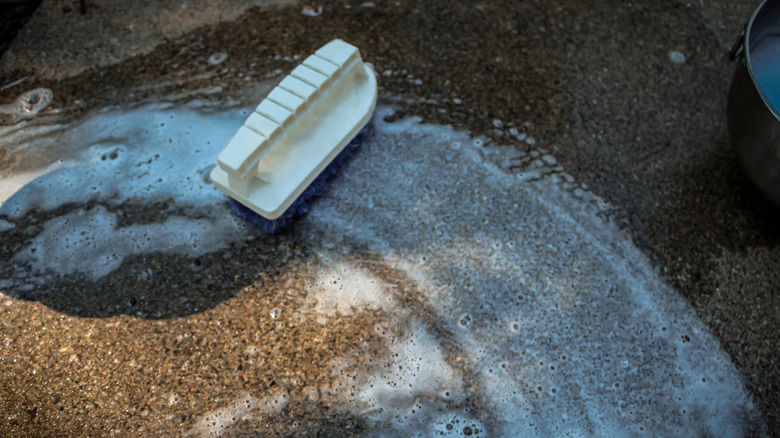 A soapy scrub brush cleaning concrete surface