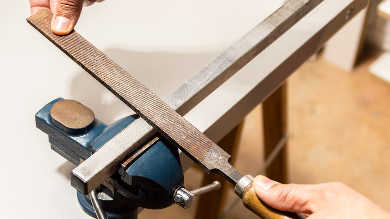 A person using a metal file with rust on it