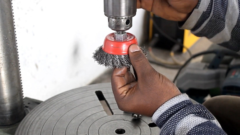 A person attaching a wire wheel to a drill press