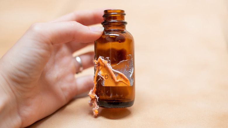 hand holding bottle with sticker residue