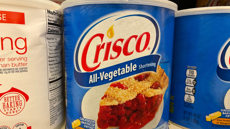 Cans of Crisco brand shortening on a grocery shelf.