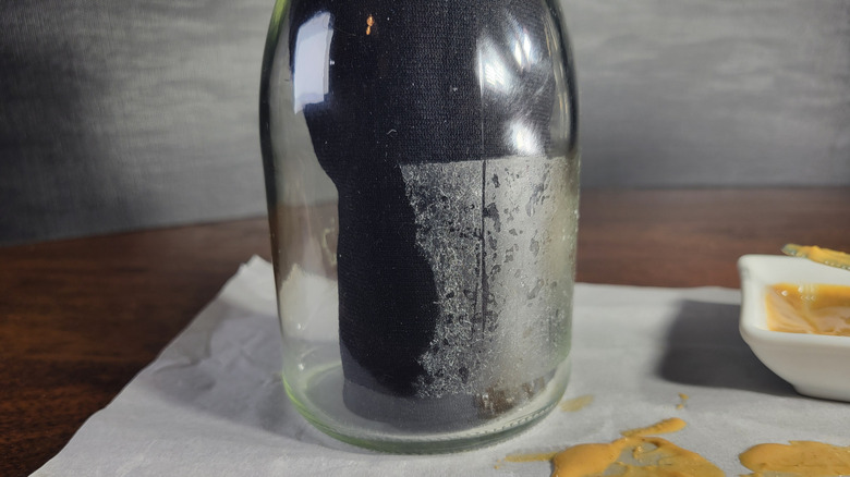 Black fabric on a bottle illustrates how cleanly peanut butter removed the adhesive from a clear plastic label
