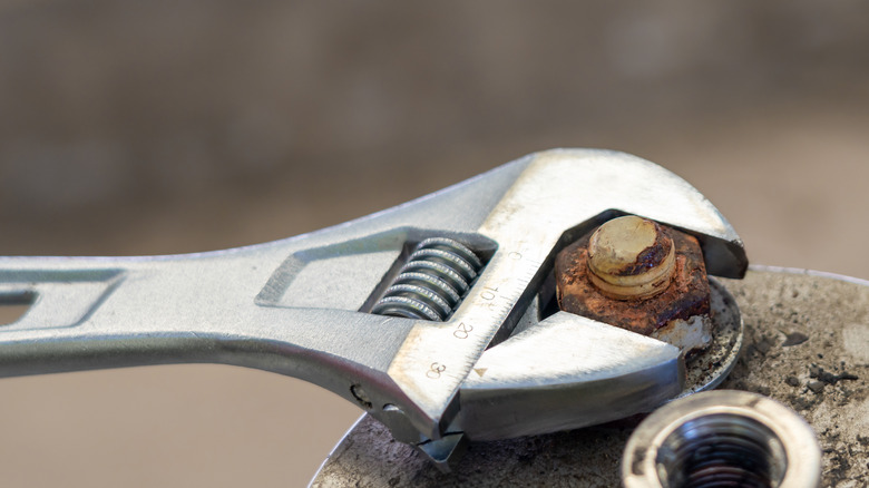 a wrench loosens a rusty bolt