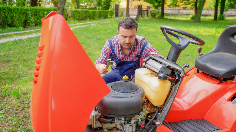 Person looking at engine of a riding lawn mower