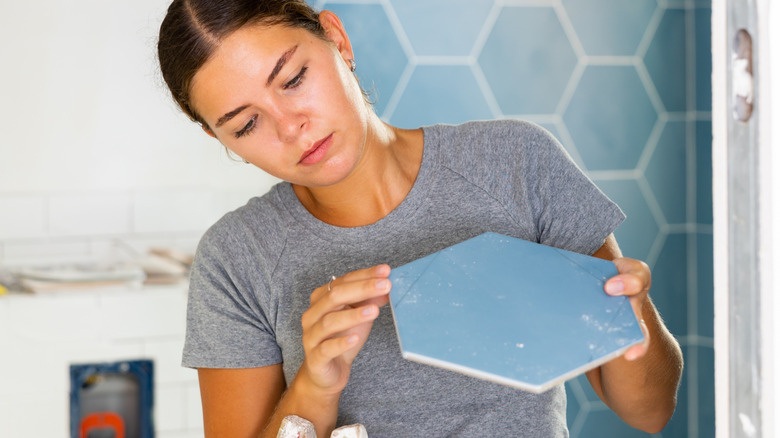 A woman stretches in bed near a small bedside table