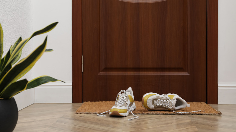 White and yellow shoes laying in an entryway by the front door