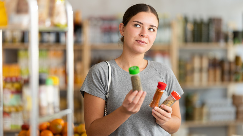 Woman holding up spice containers and thinking of a creative idea