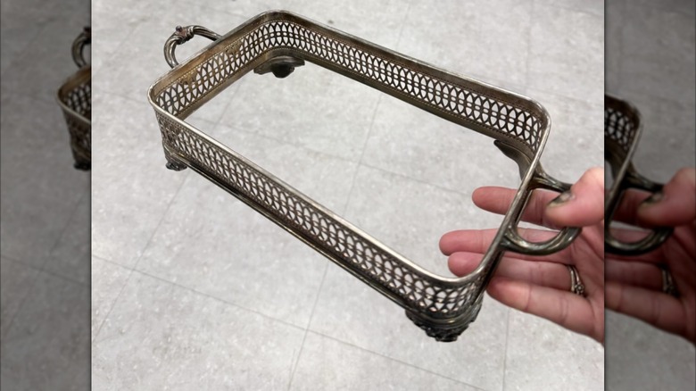 Woman holding a silver casserole holder from the thrift store