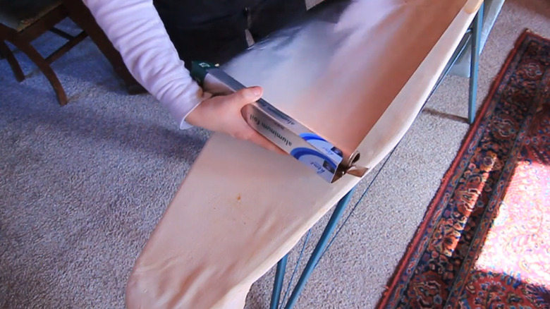 Rolling sheet of aluminum foil onto ironing board