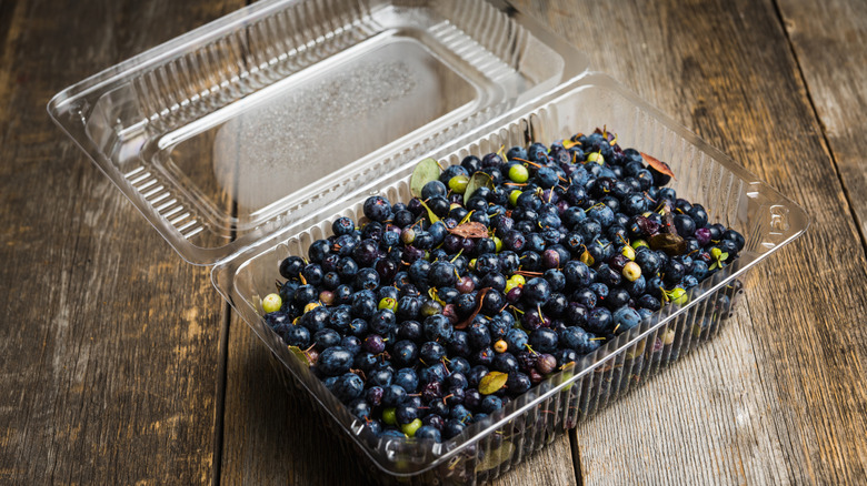 Plastic container of berries on wood table