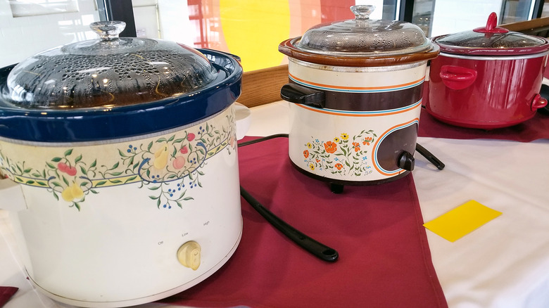 Three slow cookers on table.
