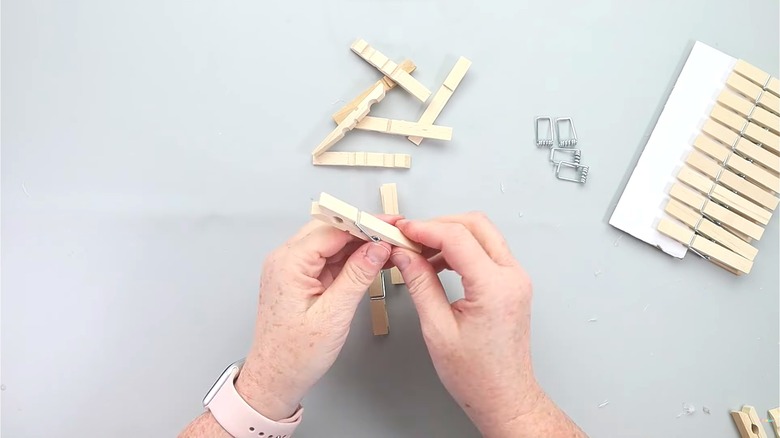 Woman with trendy smart watch crafting with clothespins over white surface