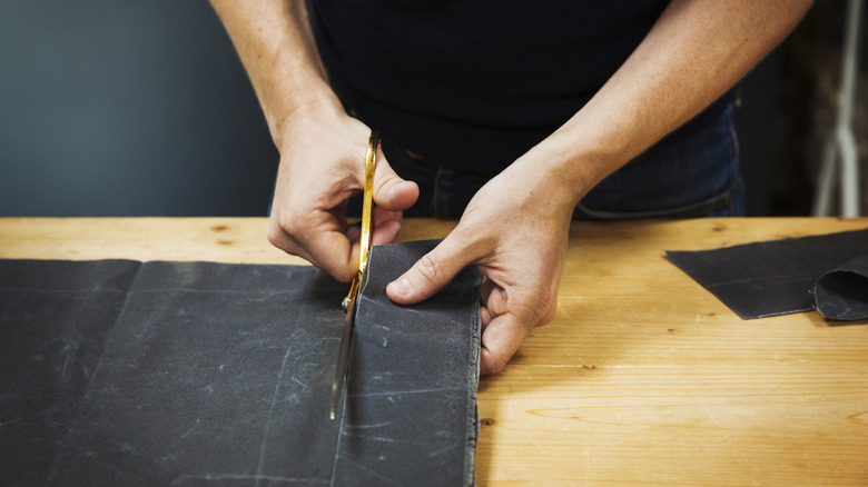 Person cutting fabric with scissors
