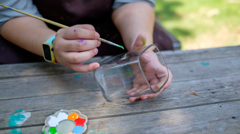 woman's hands painting glass jar