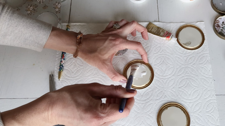 Person painting jar lids to repurpose as fridge magnets