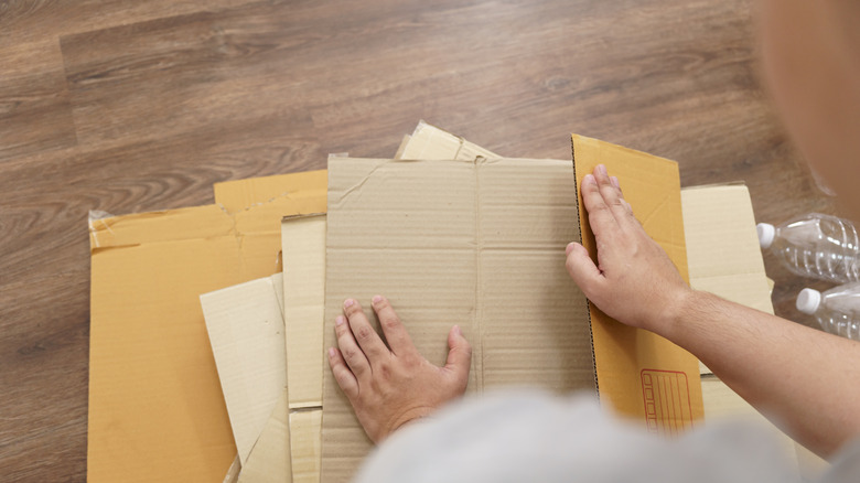 Person flattening cardboard boxes on the floor