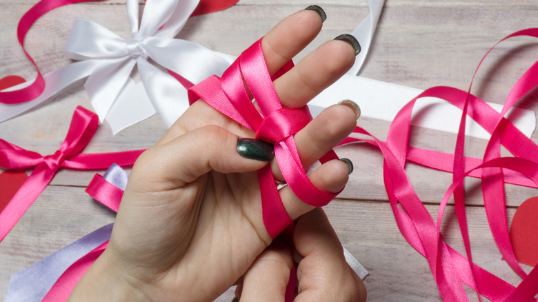 A person ties pieces of ribbon around their hand