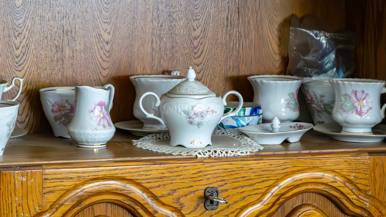 Antique teacups and kettle on a wood sideboard