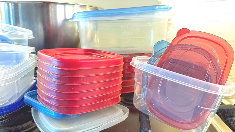Pile of empty plastic food containers in cluttered cabinet
