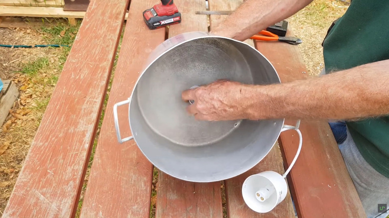 a man threads a pendant light kit onto a stockpot