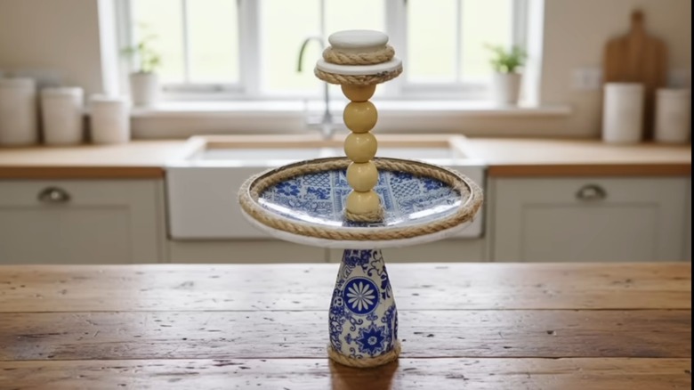 A storage tray made from a decoupaged pot lid and glass bottle.