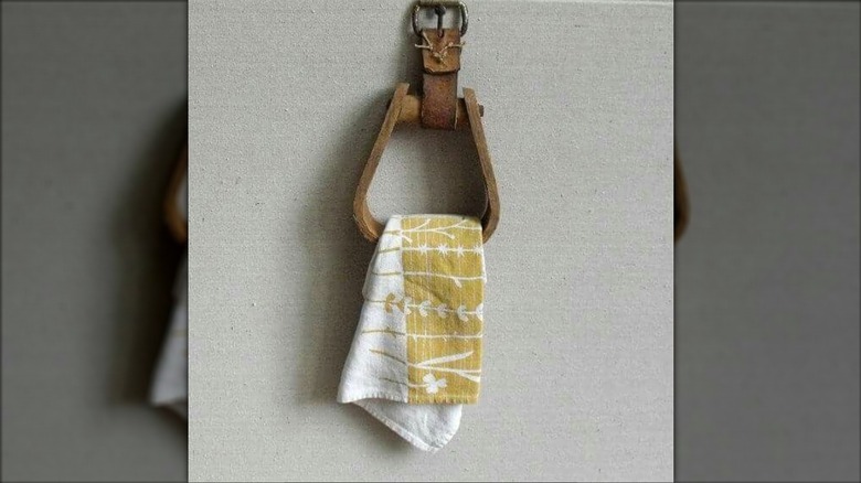 Wooden stirrup mounted to the wall holding a towel