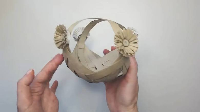 Small basket woven out of cardboard tubes with cardboard flower accents